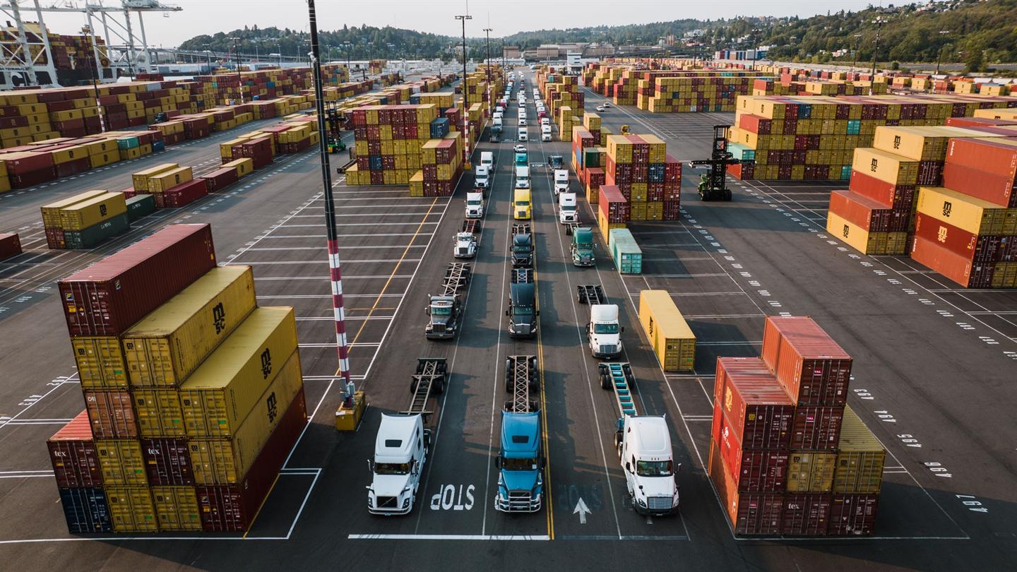 Container terminal with trucks queued between stacked shipping containers