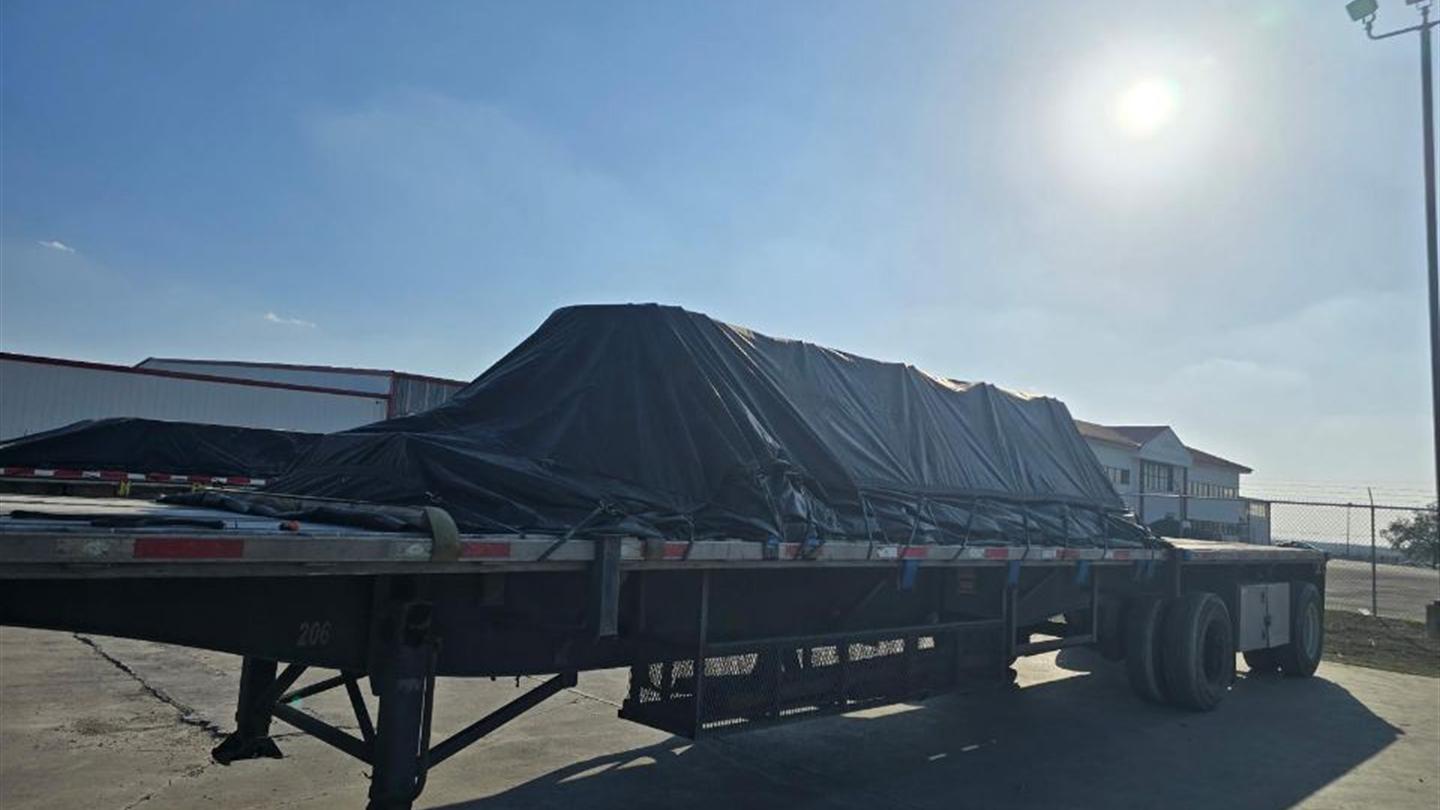 Tarped flatbed load secured for transport