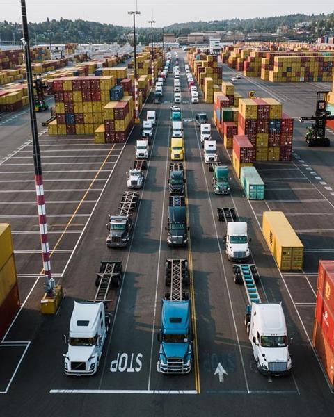 Container terminal with trucks queued between stacked shipping containers