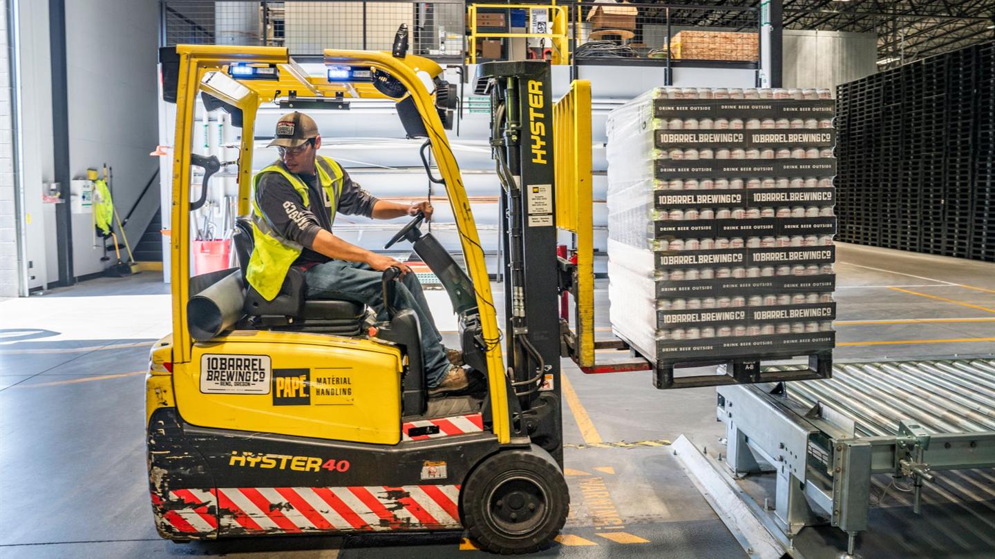 Warehouse worker operating a forklift between racks