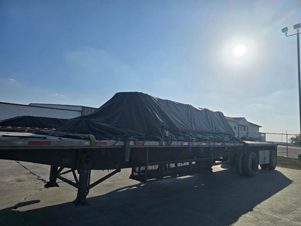 Tarped flatbed load secured for transport