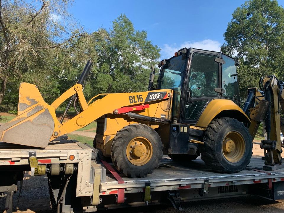 Backhoe loader loaded on a trailer for delivery