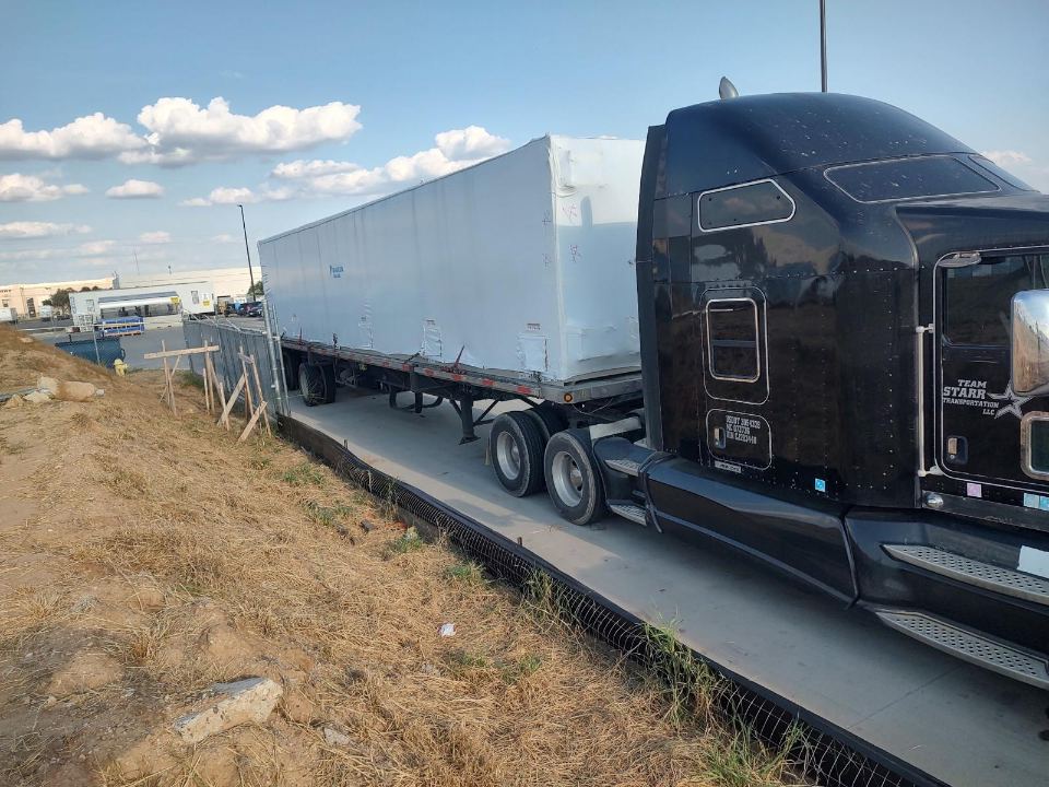 Long enclosed load secured for highway transport
